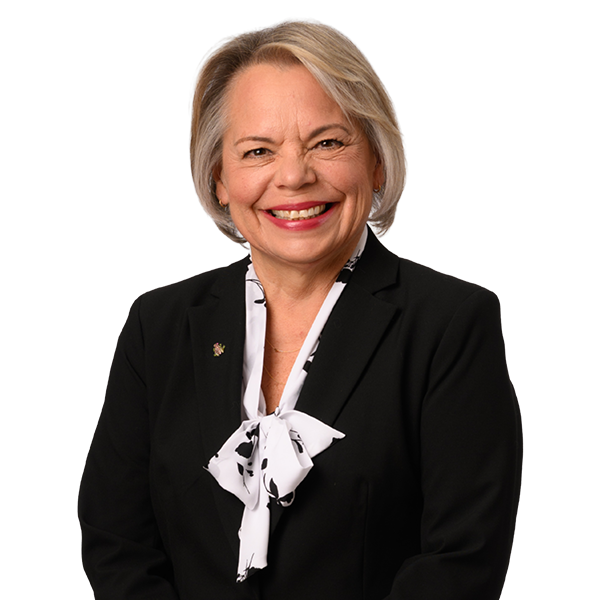Smiling woman in business attire with a black suit and white scarf.